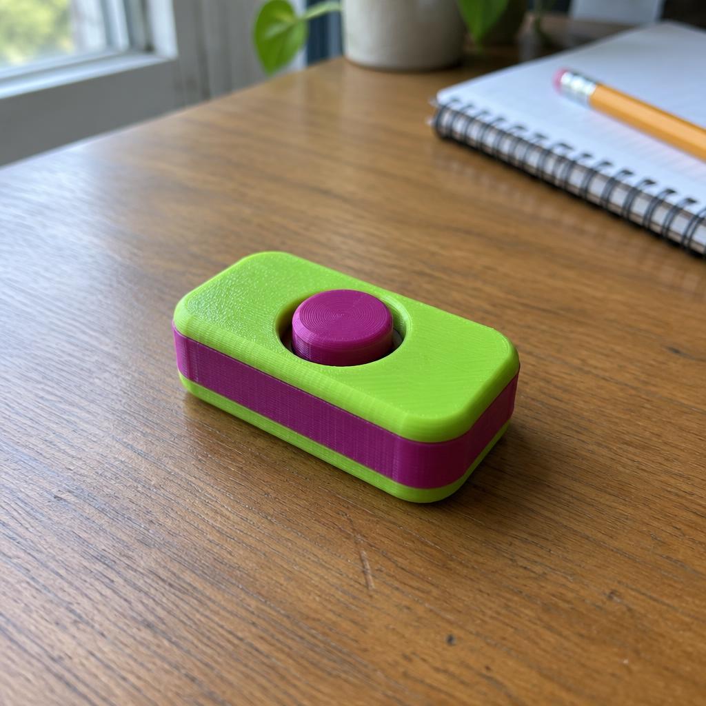 Small 3D printed fidget clicker on a wooden desk